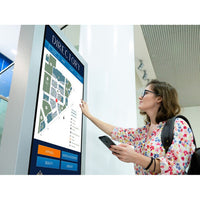Planar Systems URP752 UltraRes P Series 75" UHD 4K HDR Commercial Monitor Woman interacting with a digital directory screen in an indoor setting